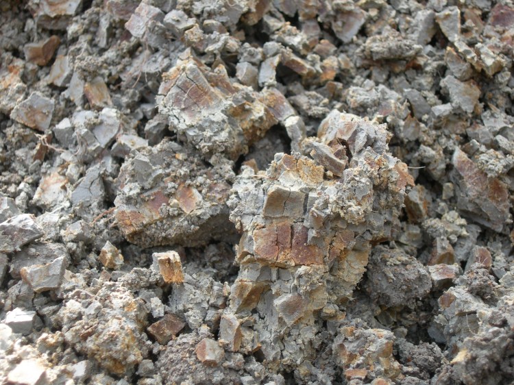 Ilman kanssa kosketuksissa ollut hapan sulfaattimaa, jolla on punaisia, keltaisia ja punaruskeita kenttiä harmaata taustaa vasten. 